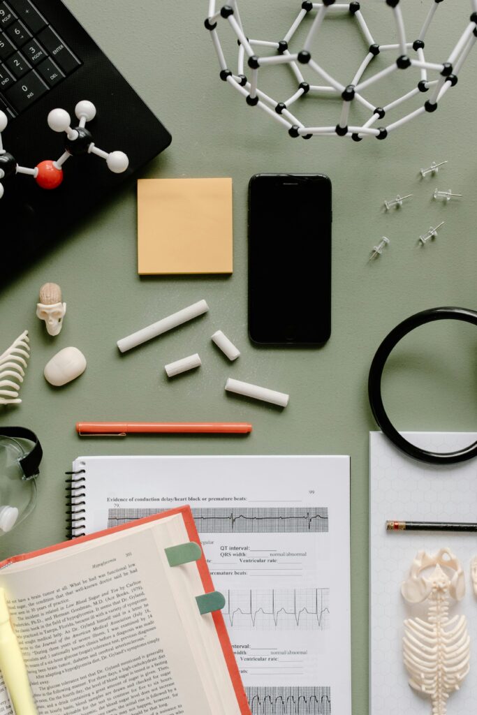 Flat lay of study materials and molecular models on a green desk, ideal for educational and scientific themes.